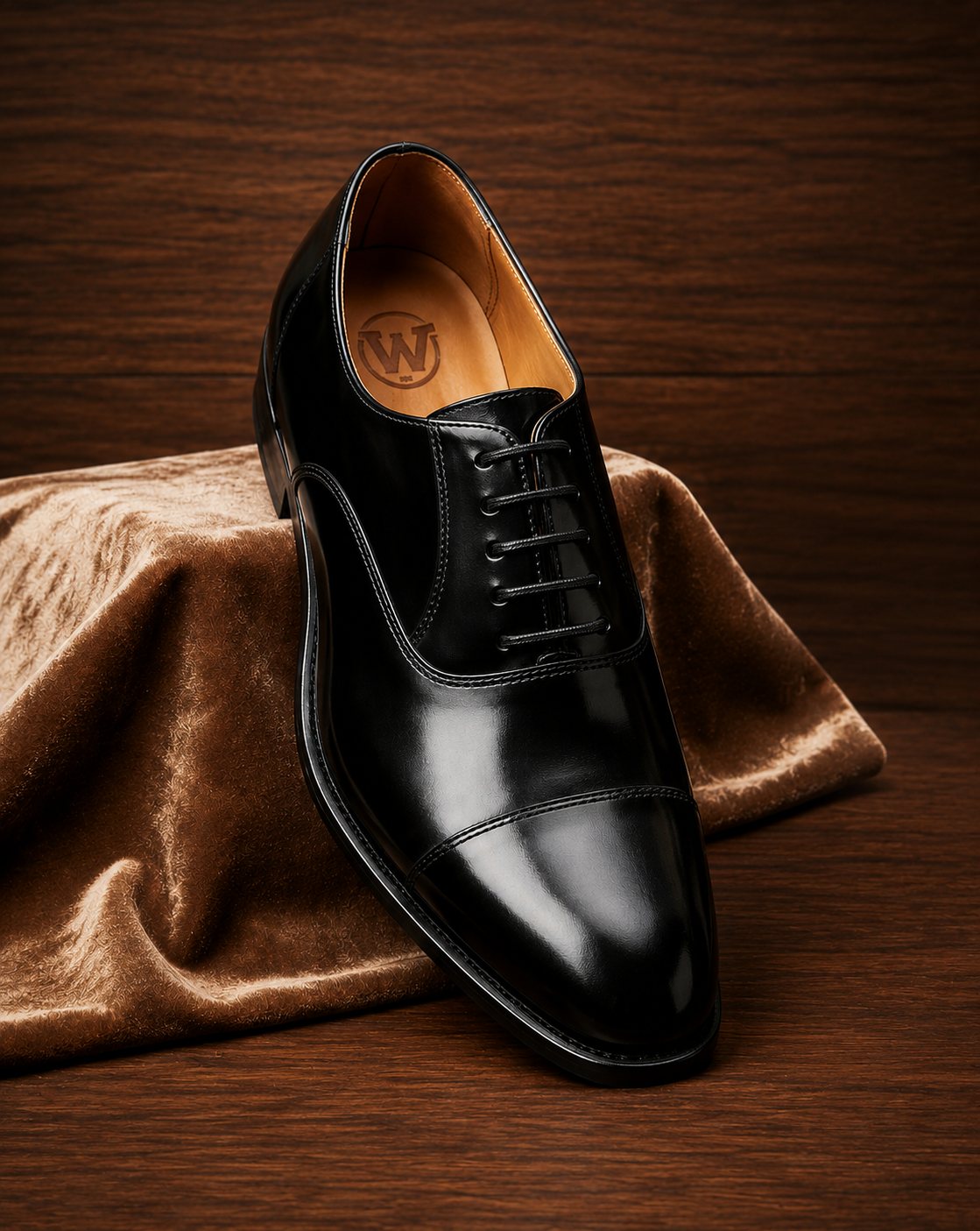 Detailed view of black leather cap-toe oxford showing closed eyelets and branded leather footbed